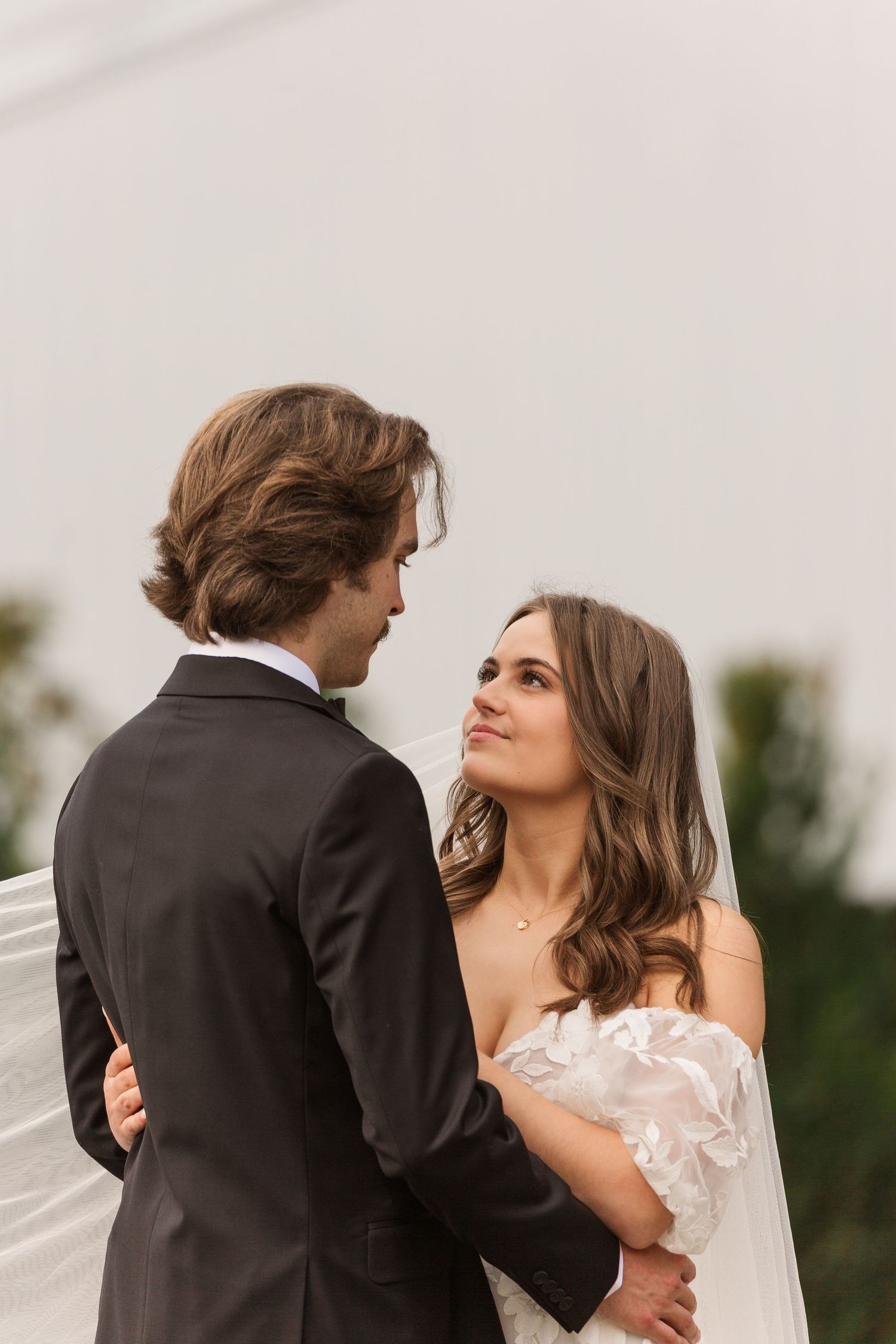 A couple in wedding attire share a romantic dance outdoors.