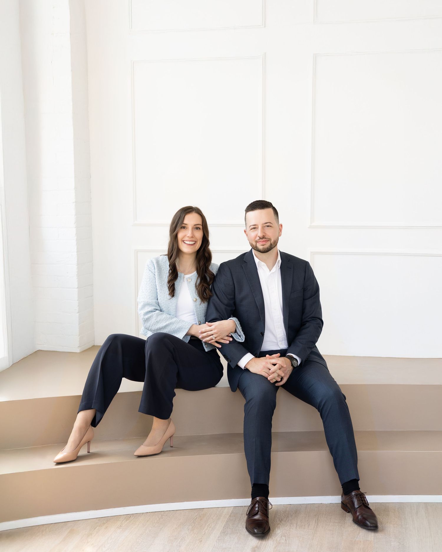Branding portrait of two real estate agent professionals seated together, showcasing confidence and partnership.