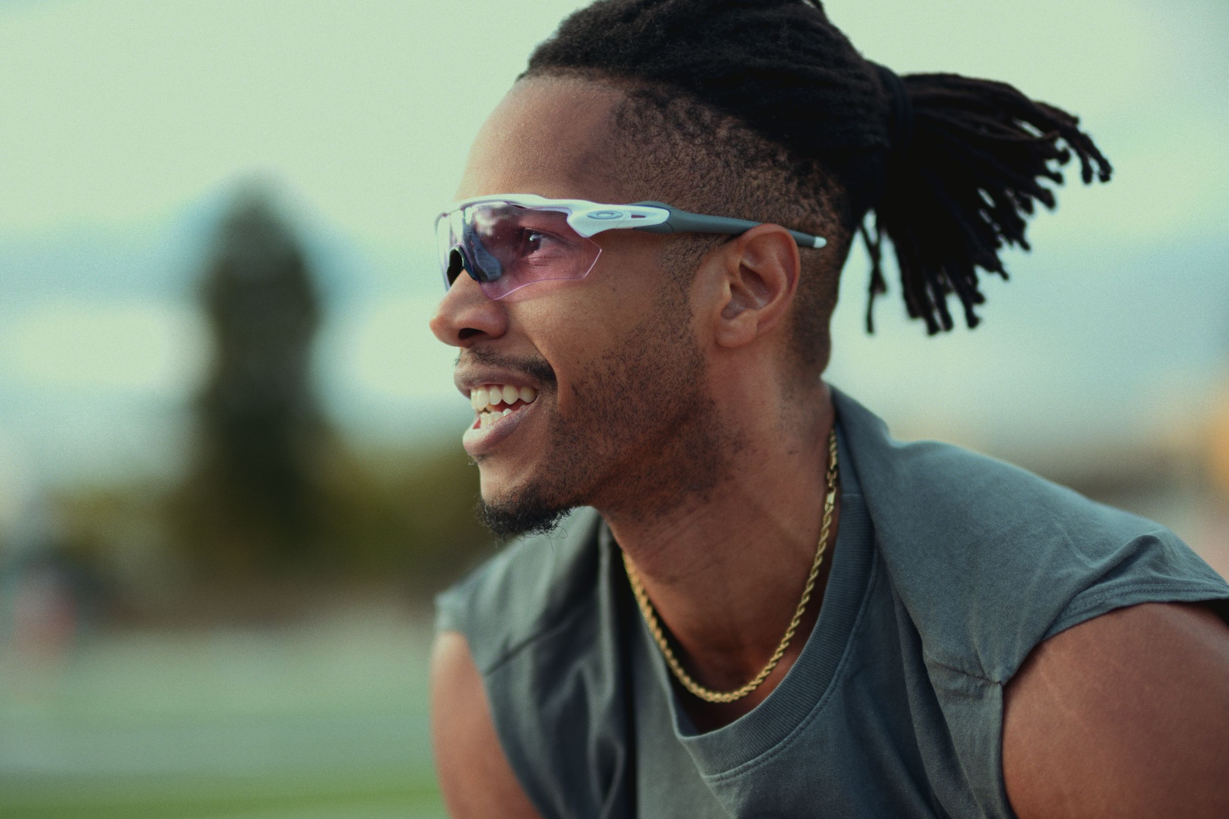 Athletes relaxing and smiling together outdoors wearing workout gear and sunglasses.