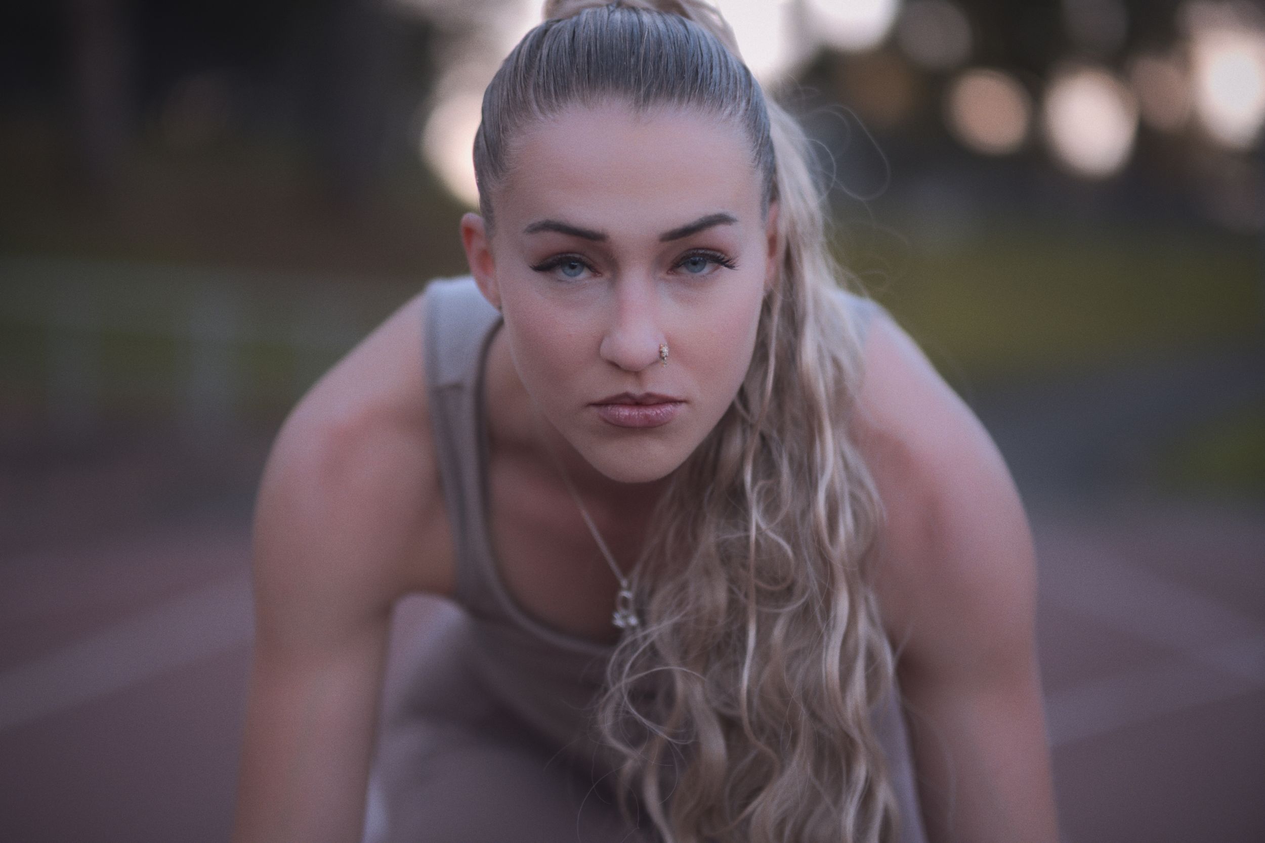 Athletic blonde woman in workout clothing strikes a series of dynamic fitness poses outdoors at dusk.