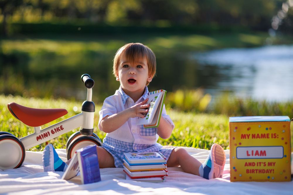 Students sitting outdoors on grass doing schoolwork and reading books on a sunny day.