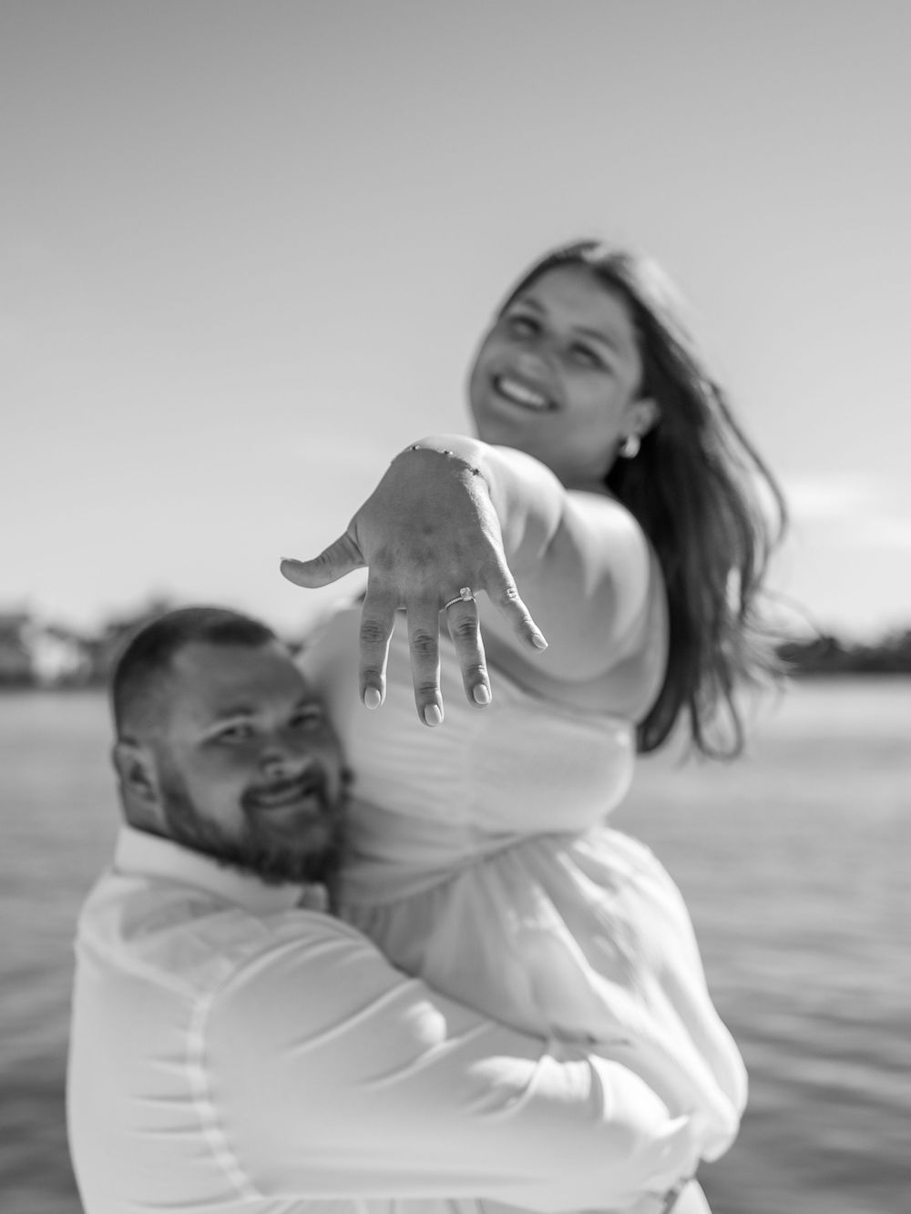 Black and white photo of a joyful couple dancing and spinning together outdoors.