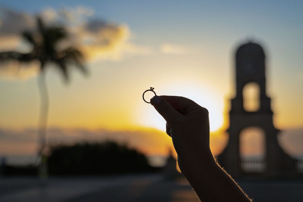 Palm trees silhouetted against a vibrant sunset sky at a tropical beach location.