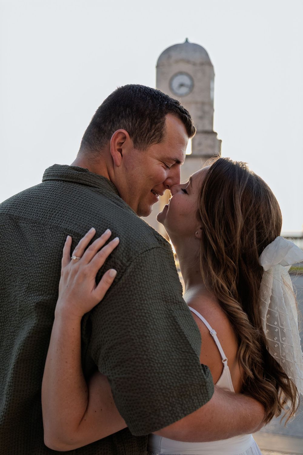 A tender moment captured between a couple in front of a stone building at dusk.