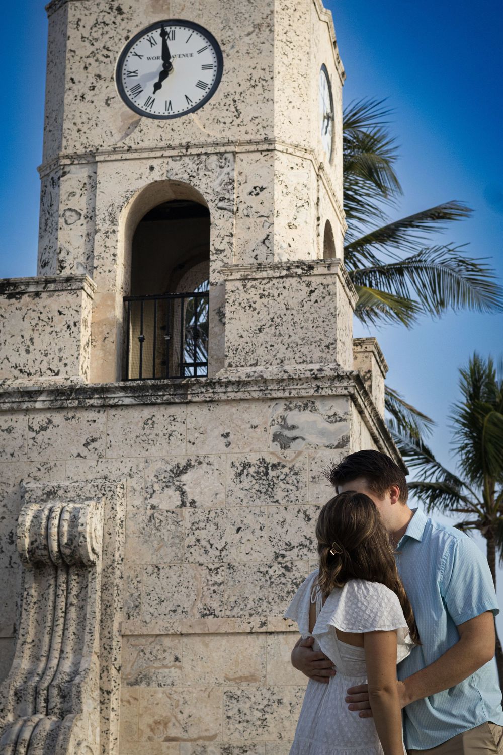 A historic clock tower with coral stone architecture against a bright blue sky.