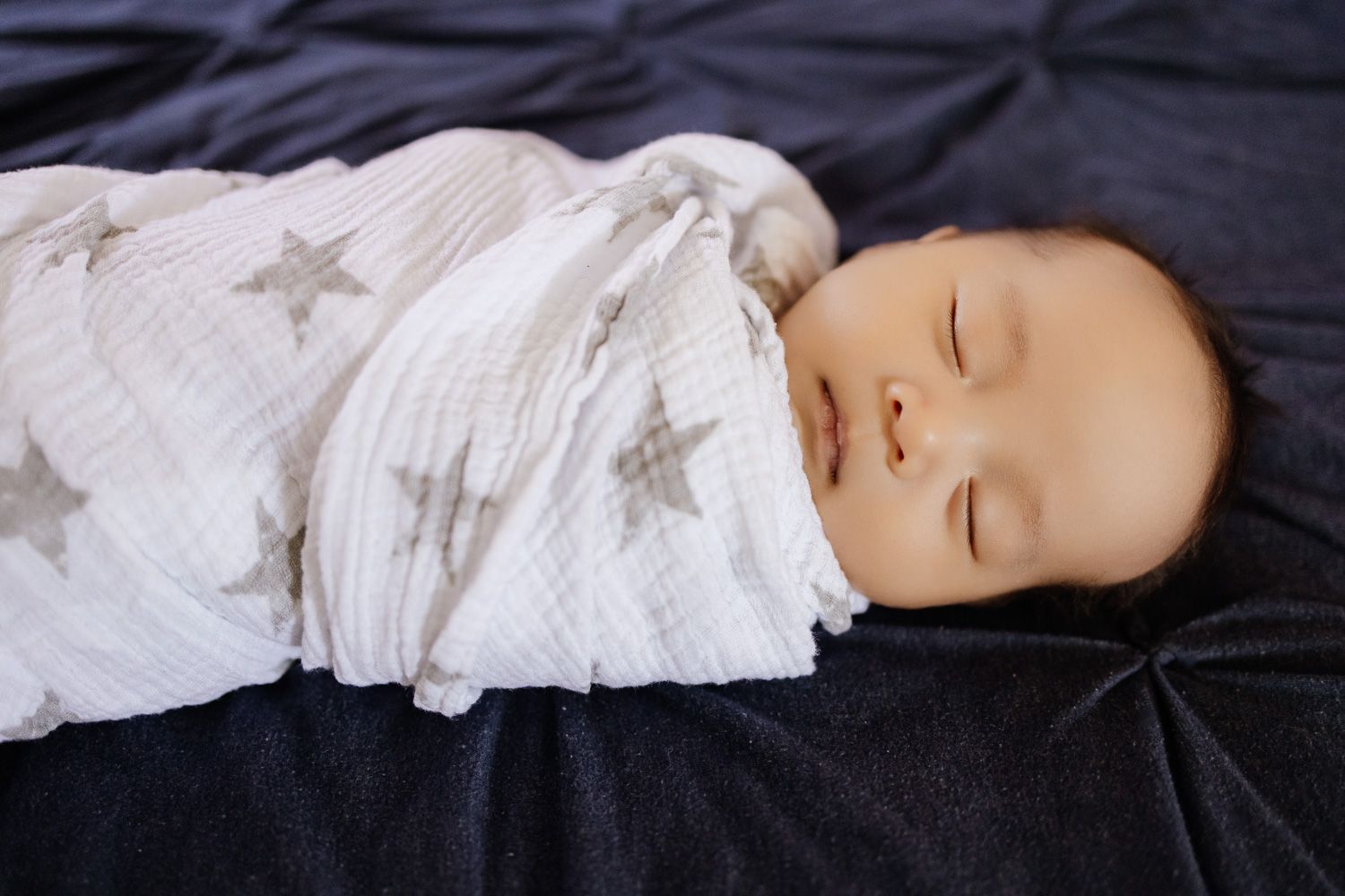 Close-up of sleeping baby swaddled in star pattern