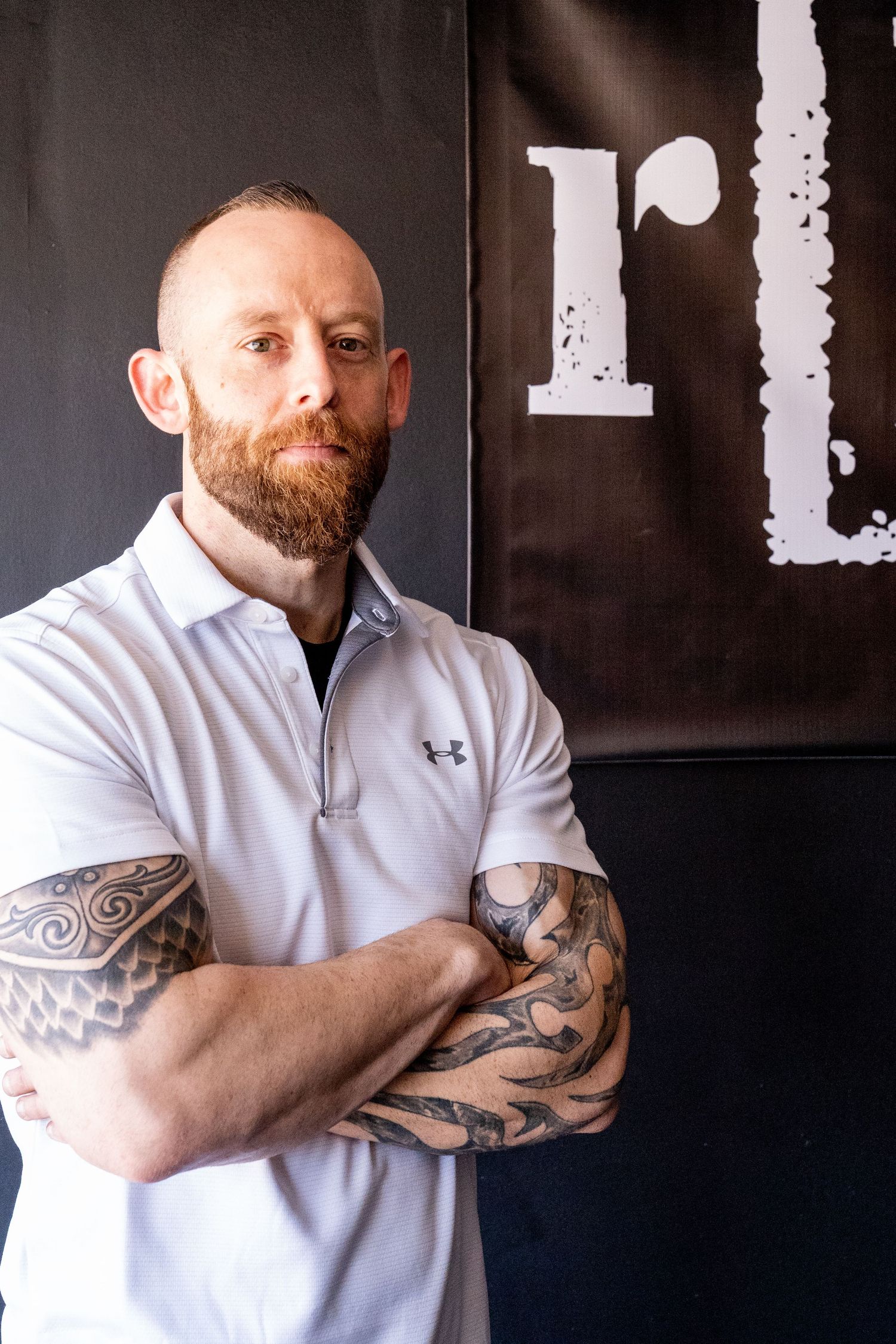 Headshot of r[E]volution Fitness gym owner standing with his arms crossed wearing a white polo.