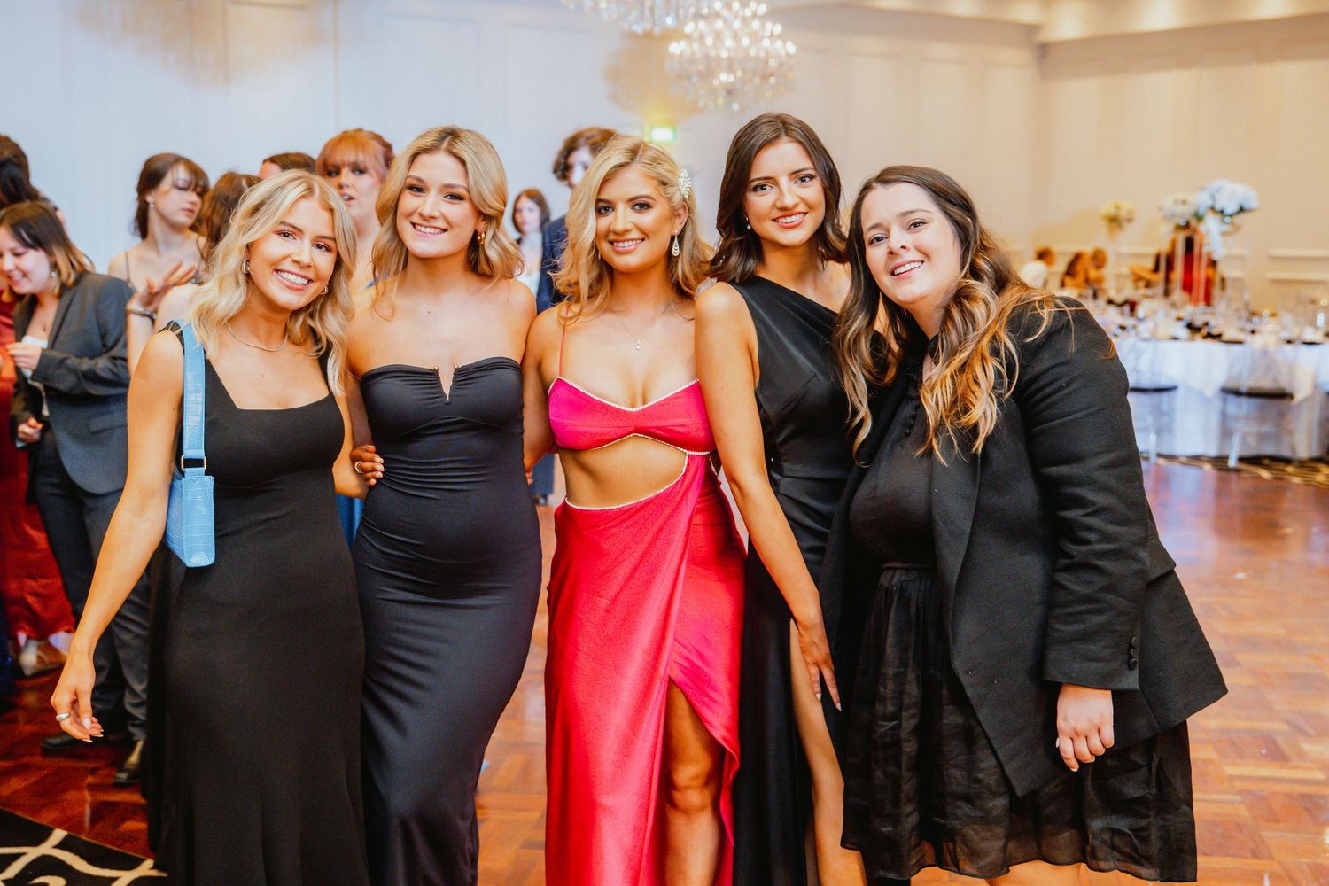 A group in formal attire poses together along an elegant staircase at a festive gathering.
