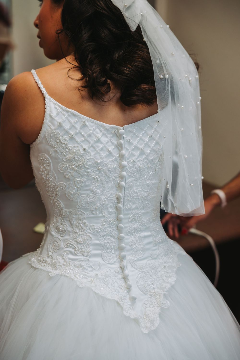Close-up views of an elegant white wedding dress featuring intricate lace detailing and beadwork on the bodice.