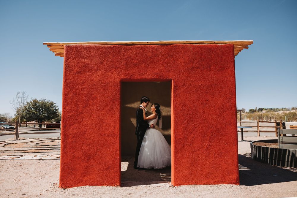 A long panoramic view of a red adobe wall with small windows stretches across a desert landscape.