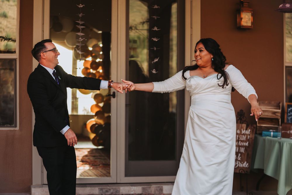 A couple in formal wedding attire dancing together during their first dance at an indoor reception venue.