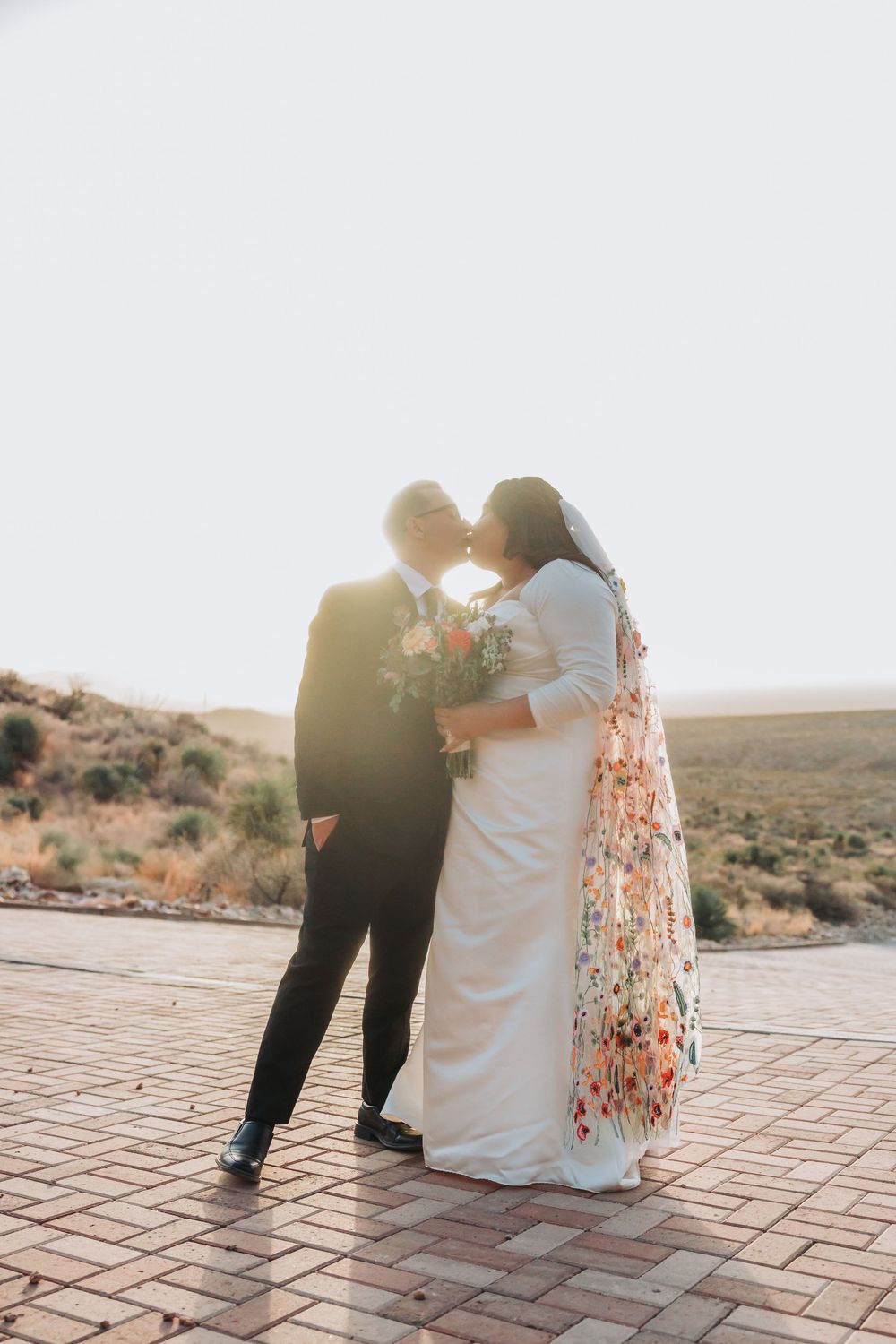 Couple sitting together on a rustic tiled patio with desert landscape in background during golden hour.