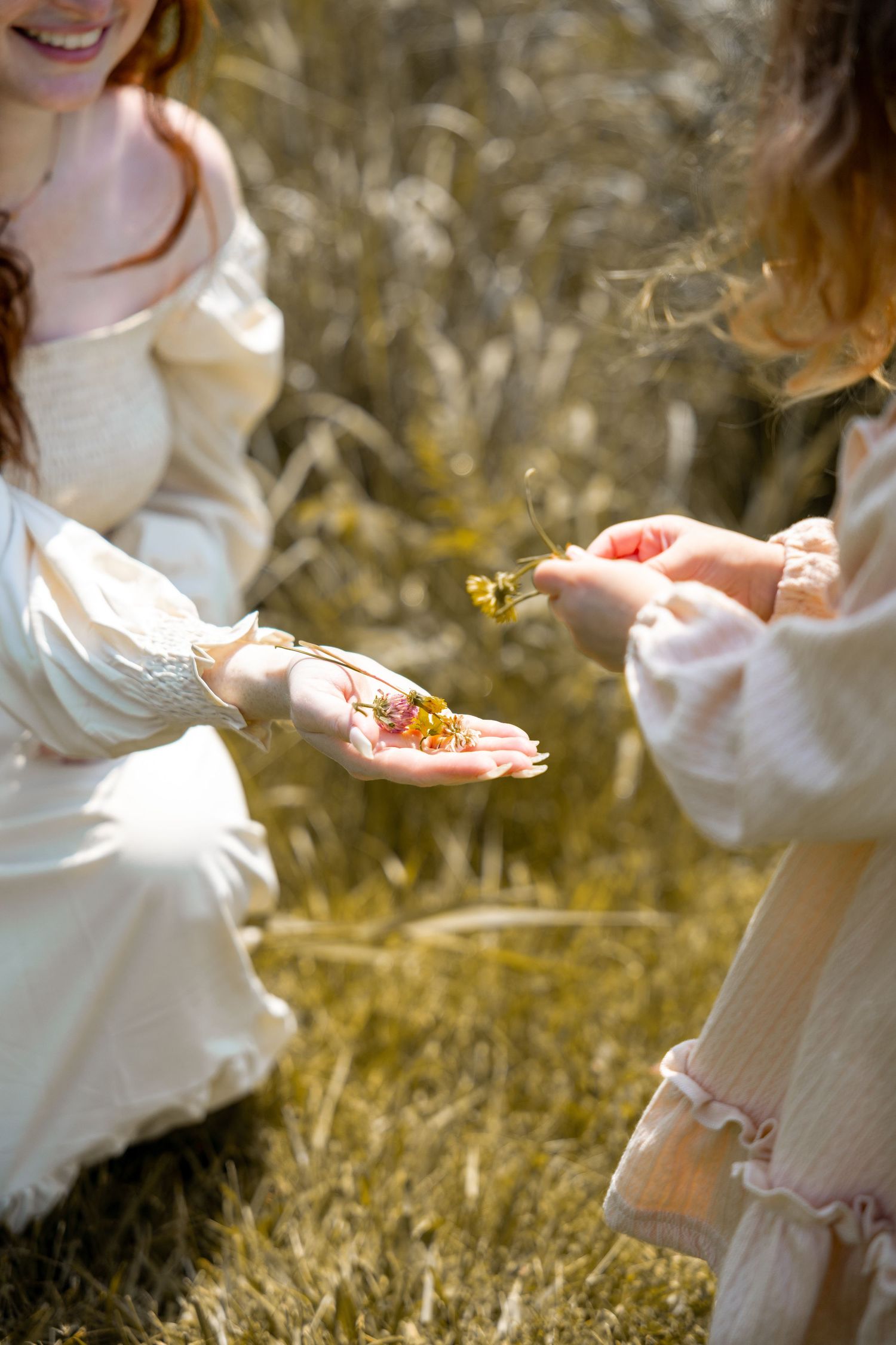 A person in a white dress sits in a grassy meadow holding out their hands to catch butterflies in golden sunlight.