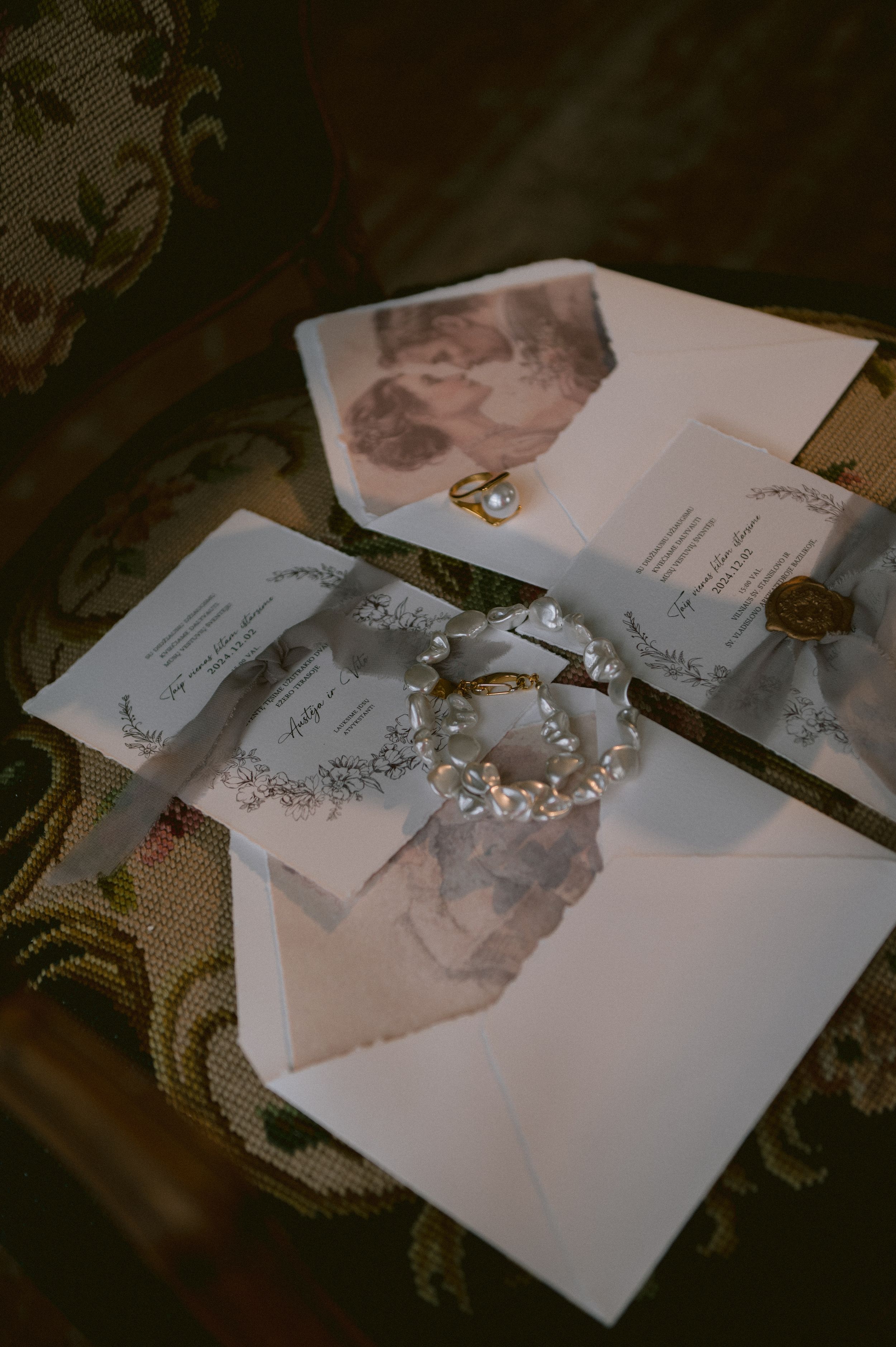 Vintage photographs scattered on an ornate fabric with a delicate pearl crown or tiara displayed in the center.
