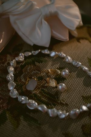 Pearl and crystal jewelry set with white bow on textured fabric background.