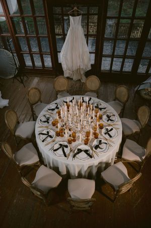 Elegant wedding reception table settings with glowing candles and white linens in a rustic venue.