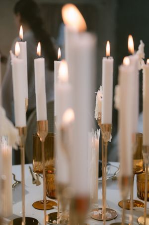 White taper candles burning in golden holders creating a romantic atmosphere.