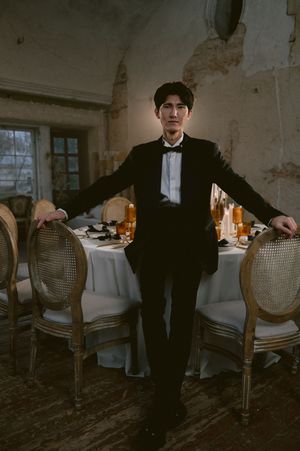 Classic formal portrait in black tuxedo against vintage dining room backdrop.