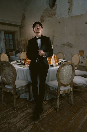 Atmospheric wedding venue with vintage furniture and white tablecloths in rustic setting.
