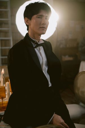 Dramatic backlit portrait in formal attire against a candlelit setting.