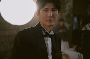 Moody portrait in formal attire with dramatic lighting and bokeh effects.