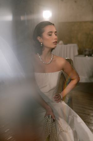 Elegant bridal portrait featuring a strapless gown and pearl accessories in soft lighting.