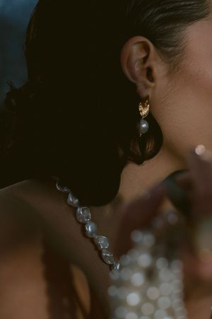 Close-up of pearl necklace and elegant earring in moody lighting.