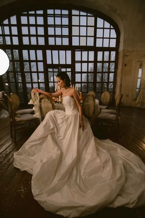 Sweeping bridal photos in white ballgown against architectural window backdrop.