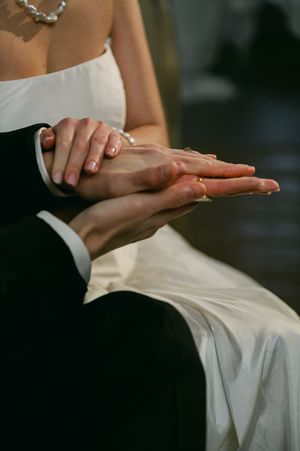 Close-up detail shots of delicate hands against white wedding dress fabric.