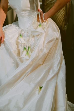 Close-up detail of a flowing white wedding dress with pearl accents and delicate fabric texture.