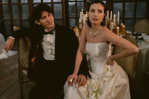 Candlelit wedding scene with couple in formal attire seated in vintage-style setting.