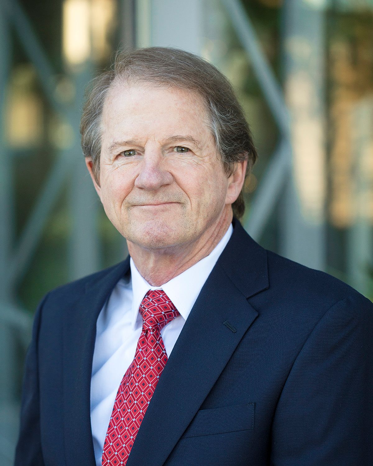 Professional portrait series of person wearing dark suit and red tie in outdoor setting.