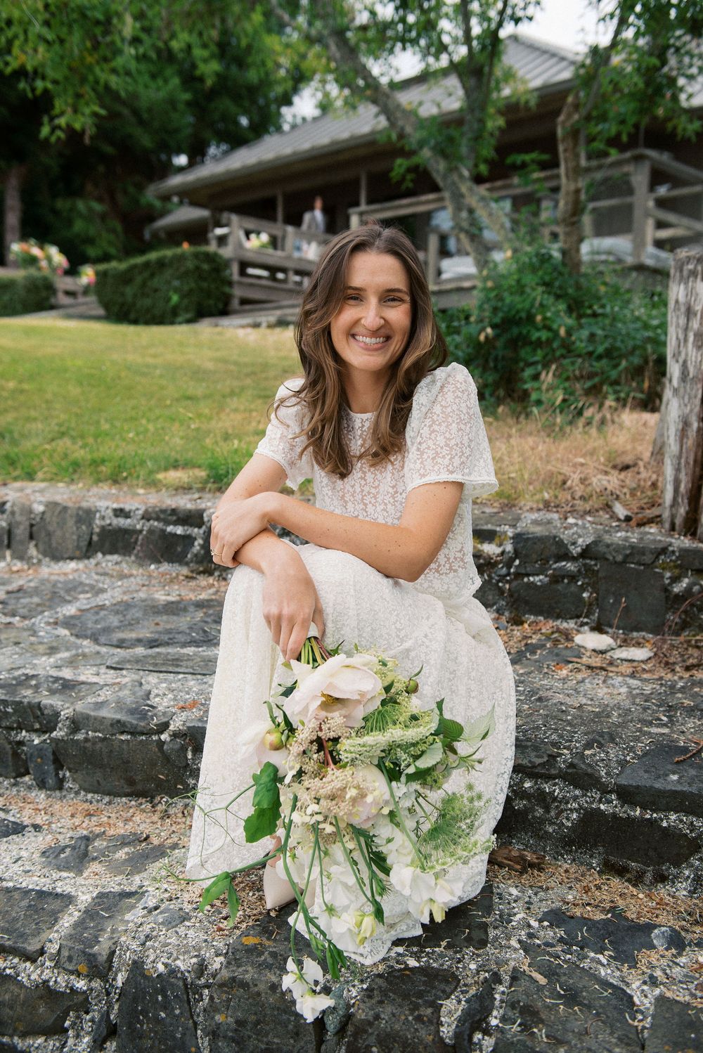 Stone wall garden setting featuring white lace dress and floral bouquet details.