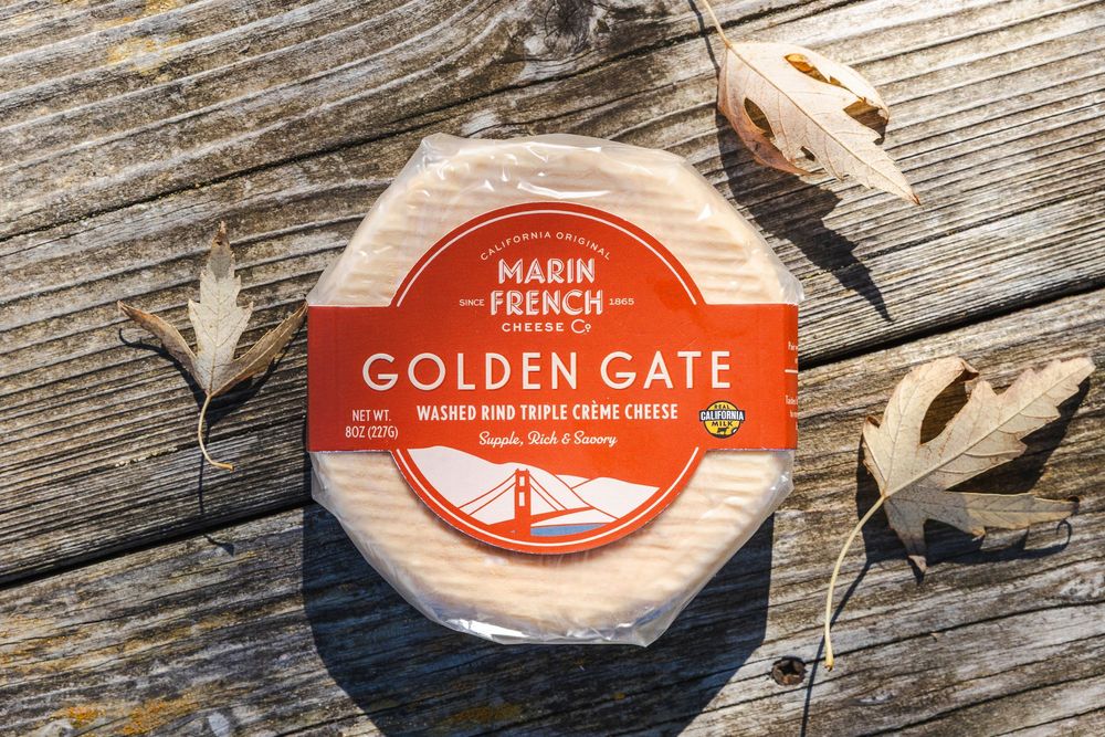 Wooden crates with vintage Marin French Cheese Co. and Golden Gate logos arranged on rustic wooden surface.