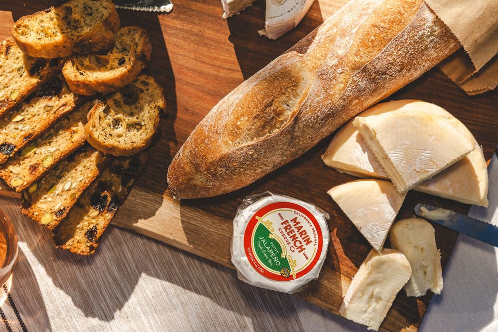 Freshly baked artisanal bread loaves and pretzels displayed on a wooden cutting board with dipping sauce.