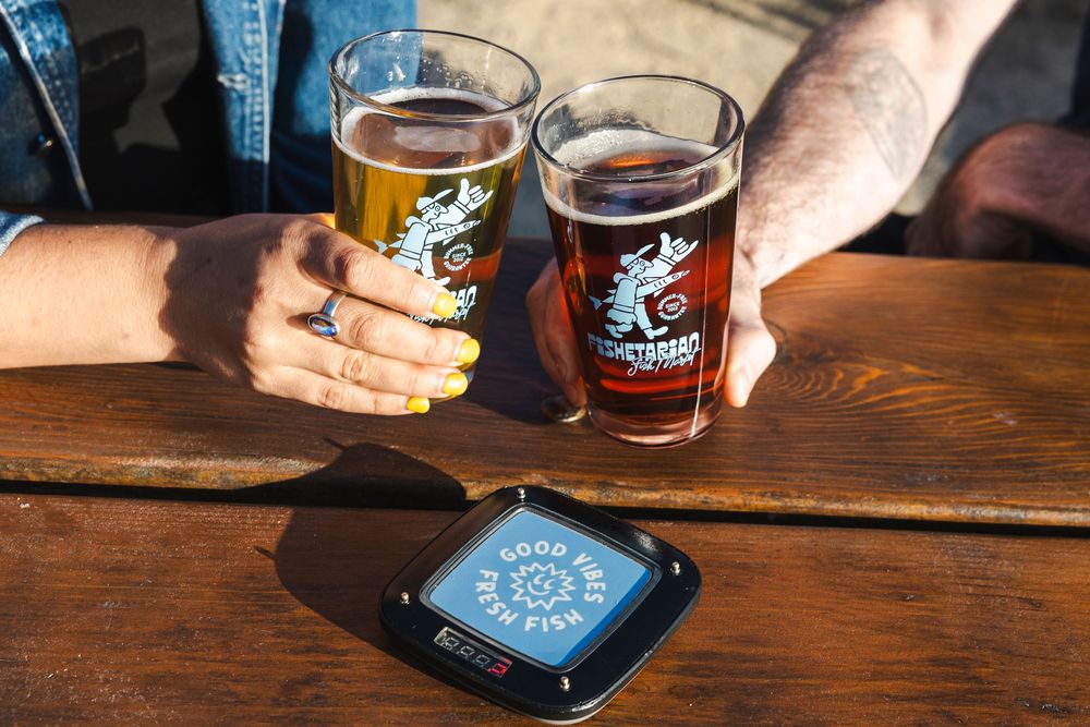 Beer glasses and mobile phones on a rustic wooden table in a pub or restaurant setting.