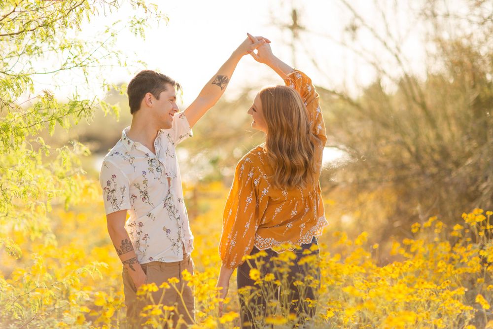 A couple dancing together among yellow wildflowers during golden hour.