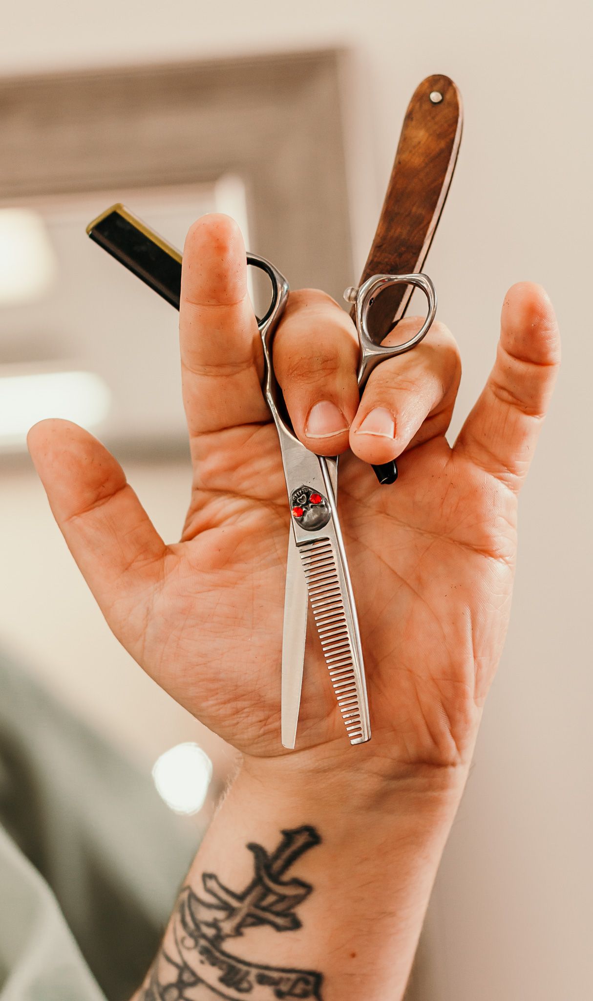 Hand holding silver scissors shows tattoo on palm while demonstrating cutting technique in progressive sequence.