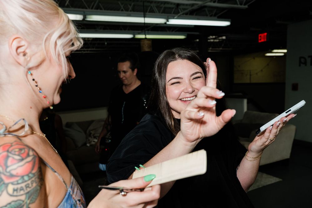 People interacting and appearing excited while holding papers in what looks like a backstage area or hallway.