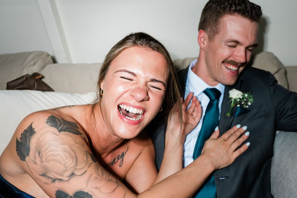 A couple share joyful laughter and embrace during what appears to be a wedding celebration.