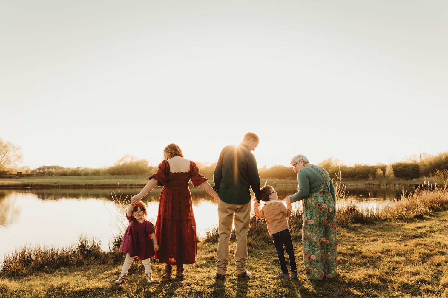 People enjoy a playful moment together in a golden field at sunset with wildflowers blooming around them.