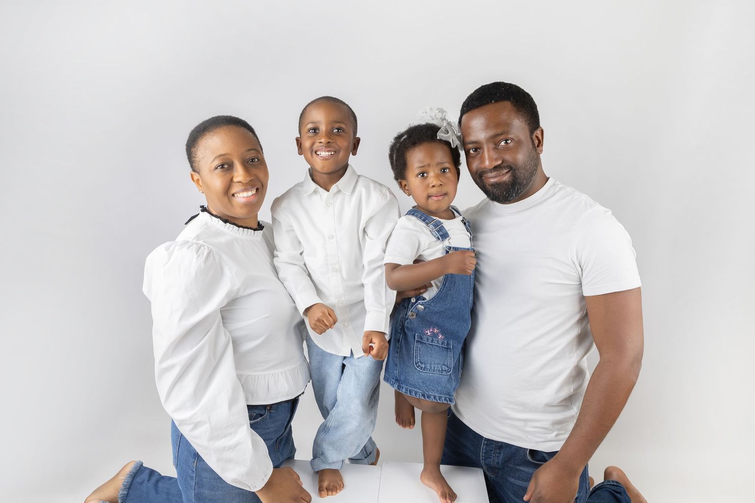 Family portrait against white background wearing coordinated white and denim outfits.