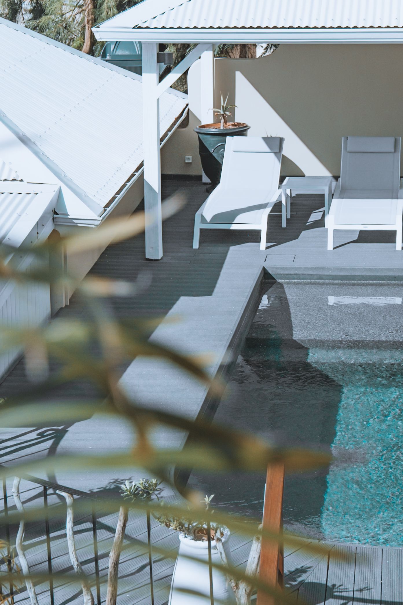 White lounge chairs with blue cushions sit beside a tranquil swimming pool at a luxury resort.