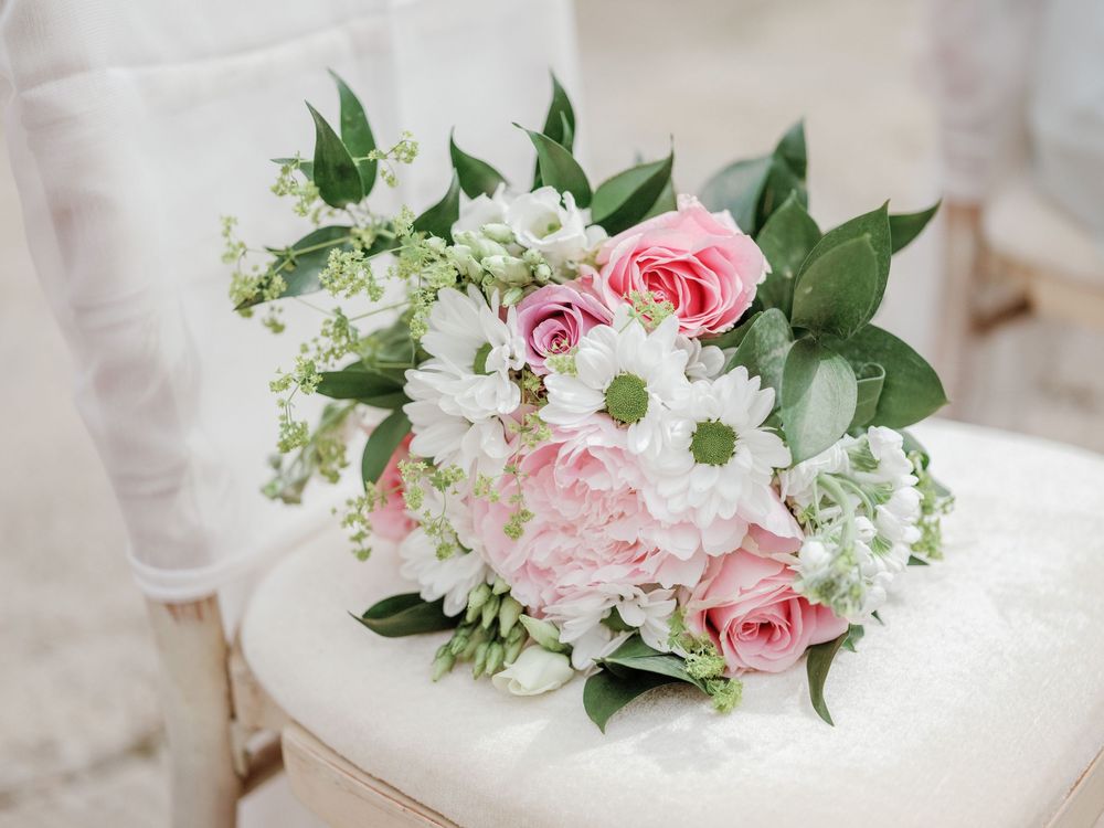 Pink roses and white wedding flowers on a chair.