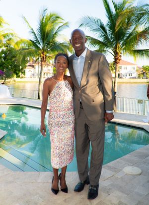 Elegant couple posing together poolside at a tropical Florida home with palm trees behind them.