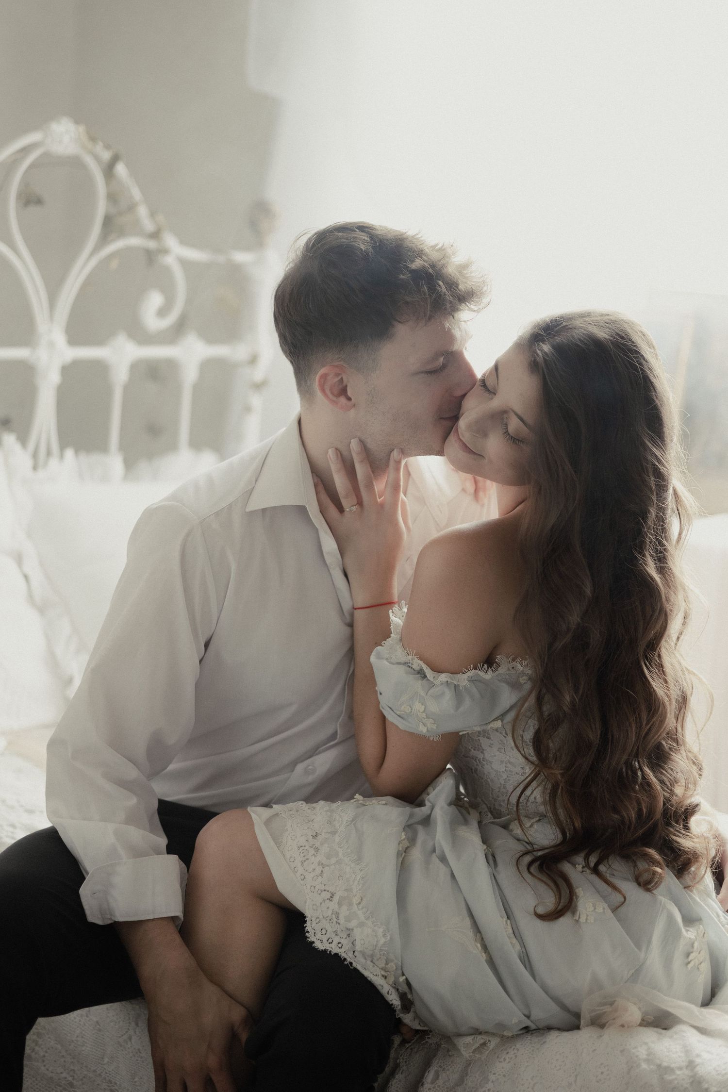 A romantic intimate moment captured in soft dreamy light with a vintage headboard in the background.