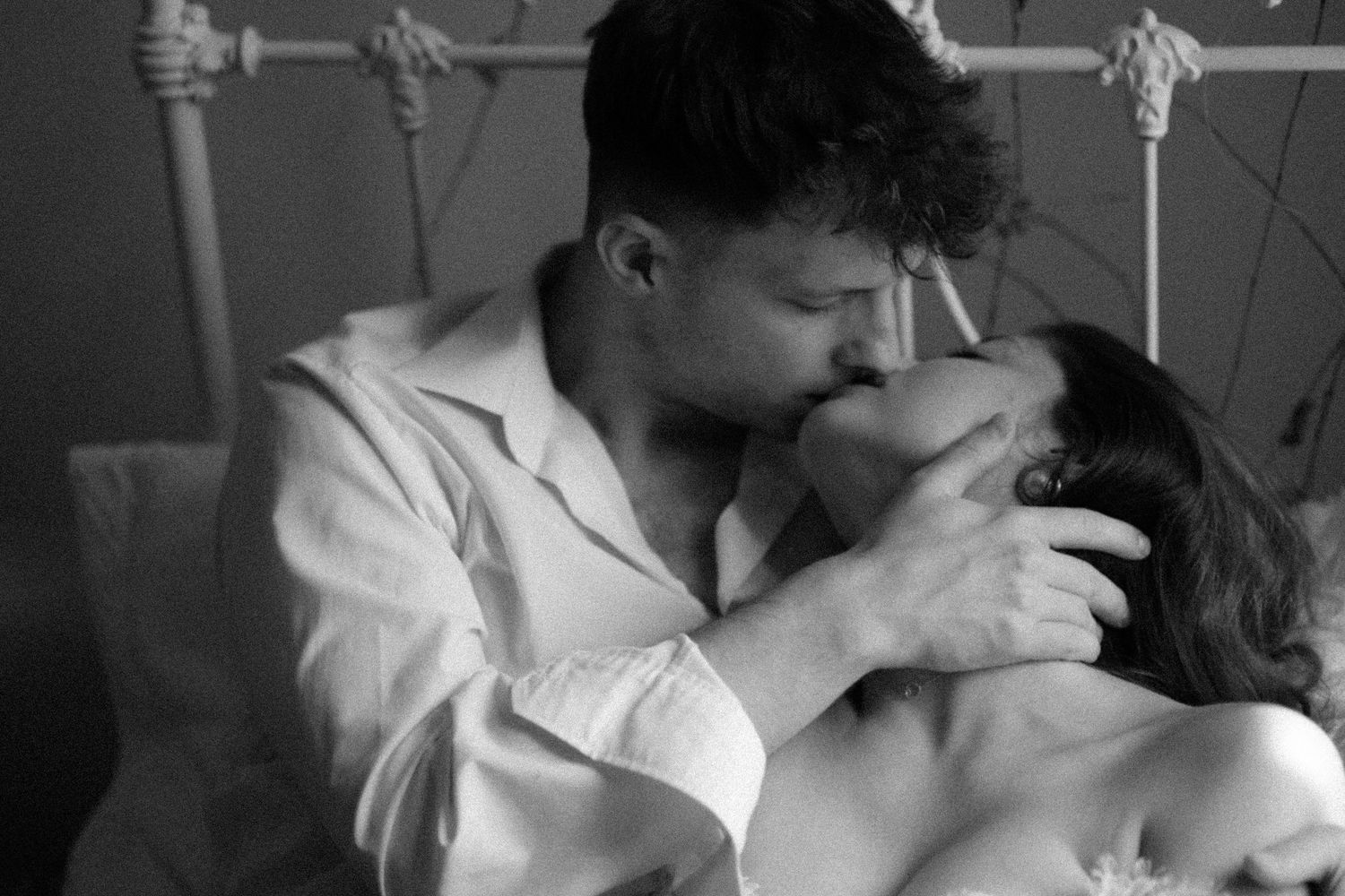 A tender black and white photograph of a romantic kiss shared between two people in a hospital bed.