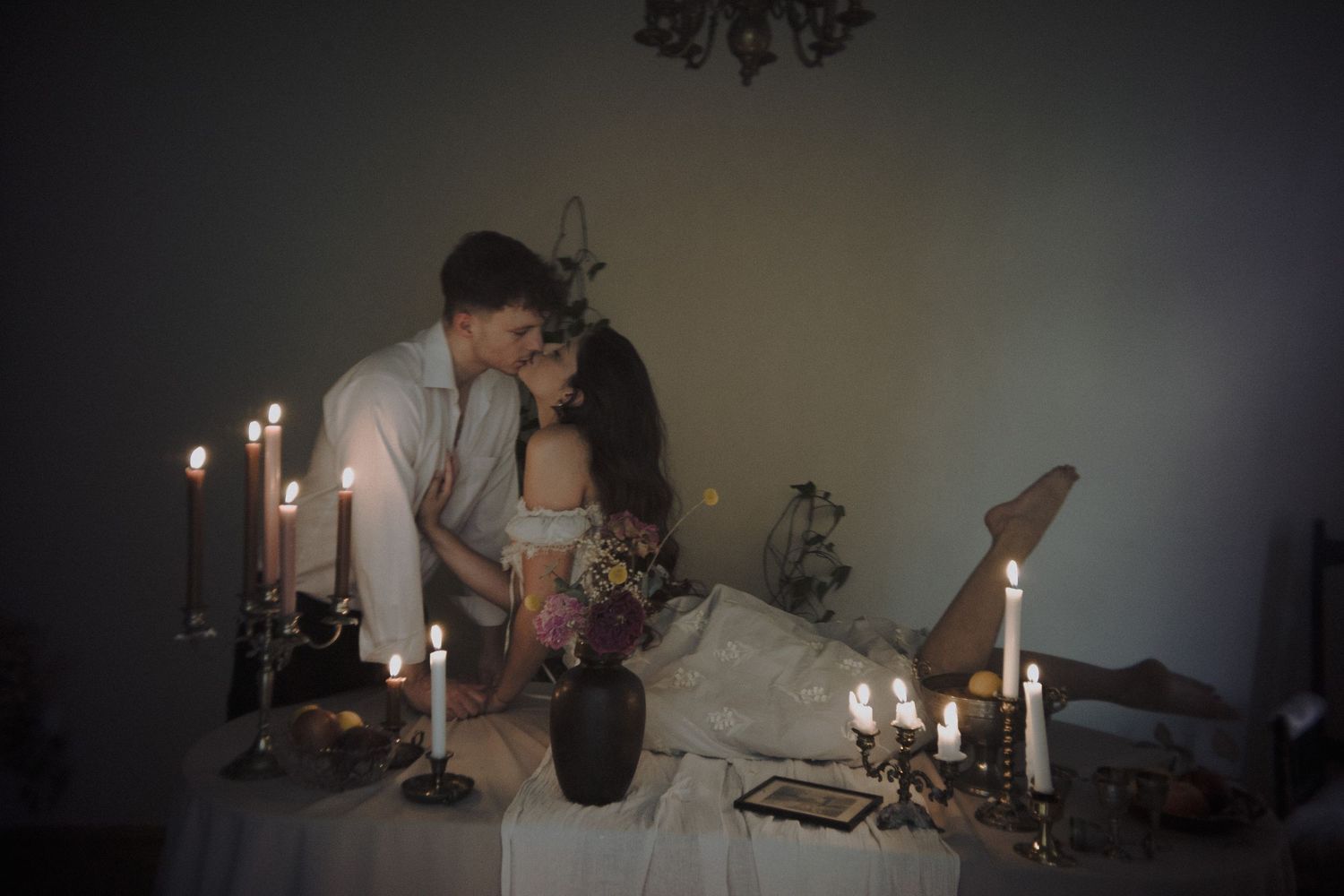 A romantic candlelit scene with people sharing an intimate moment at a table with glowing candles.