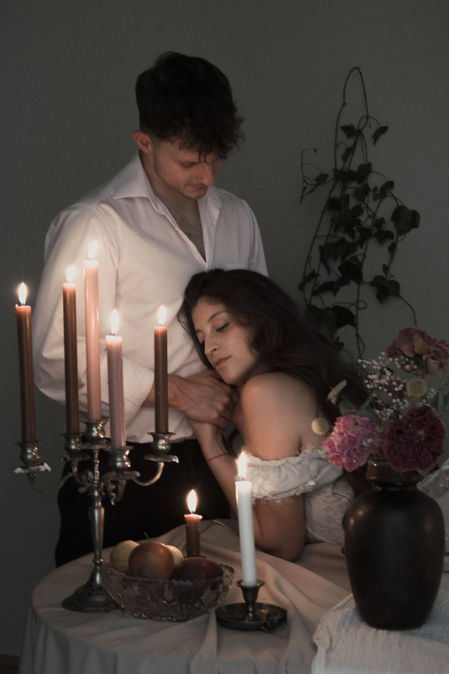 A romantic candlelit scene with a couple in white embracing across multiple moody, atmospheric photographs.