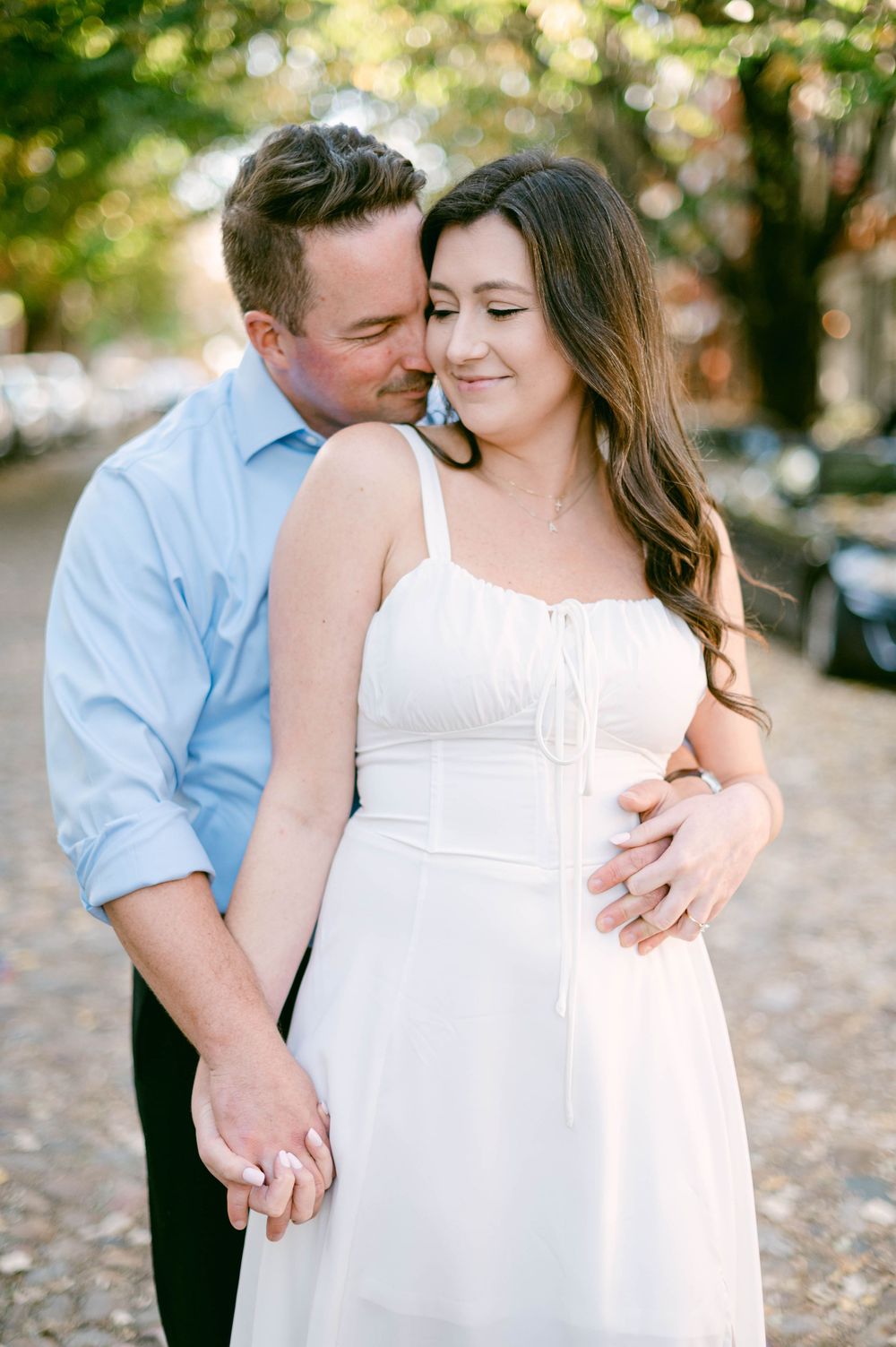 Intimate outdoor engagement photo with couple in casual formal wear.